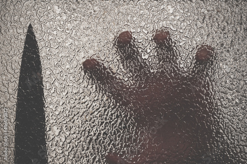 Knife in hand. Aggressive tin attack. Hacking attempt. The criminal behind the glass. Agony crooked hand. Criminal and victim, resisting the hands of the victim and attacking hand with a knife