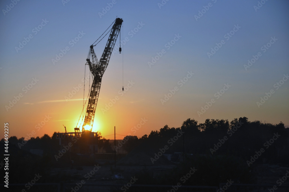 Industrial construction crane against the backdrop of the setting sun. Industrial construction crane against the backdrop of the setting sun.