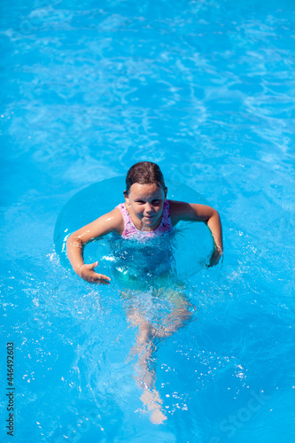a happy girl swims in a swimming pool in an inflatable circle for safety on the water, with copy space. 