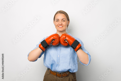 Photo of blonde young business woman with boxing gloves ready for a fight, over white background