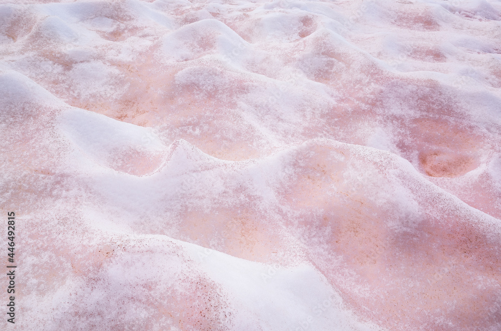 Fototapeta premium White and pink melted snow interspersed with red lies bumps