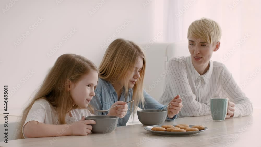 Family Having Breakfast, Mother And Daughters Eating Cereal In Kitchen Family Having Breakfast, Mother And Daughters Eating Cereal In Kitchen
