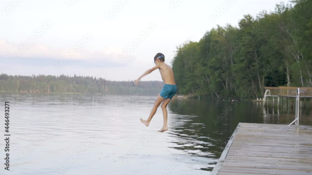 Little boy jumping into the lake from wooden pier. Having fun on summer day. Child diving in to the water from the dock. Little boy jumping into the lake from wooden pier. Having fun on summer day. Child diving in to the water from the dock.