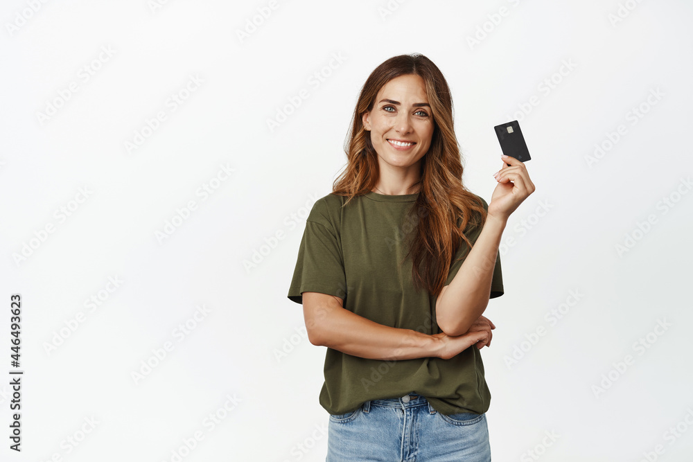 Image of smiling woman easy paying contactless, showing credit card and looking carefree, buying with discount, standing against white background Image of smiling woman easy paying contactless, showing credit card and looking carefree, buying with discount, standing against white background