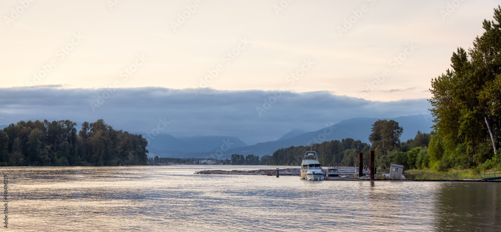 View of Fraser River and boats docked at a quay during summer sunset. Between Barnston Island and Surrey in Vancouver, British Columbia, Canada.