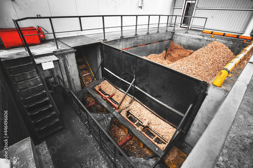 Wood chip storage bin for heating solid fuel industrial boilers with a screw chip feeding system. A concrete tank filled with shredded waste from the wood industry.