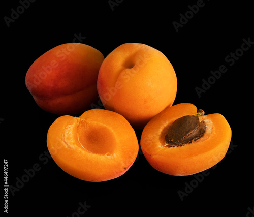 Ripe apricot, whole and in parts, on a black background, isolated photo