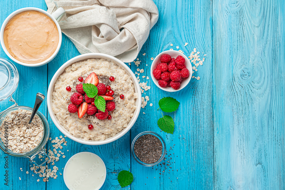 Oatmeal with raspberries, red currants, strawberries and chia seeds on a bright blue background. Oatmeal with raspberries, red currants, strawberries and chia seeds on a bright blue background.