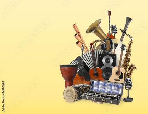 Group of different musical instruments on yellow background, space for text