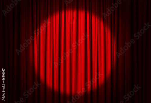 Spotlight illuminating closed red stage curtains. Start of performance