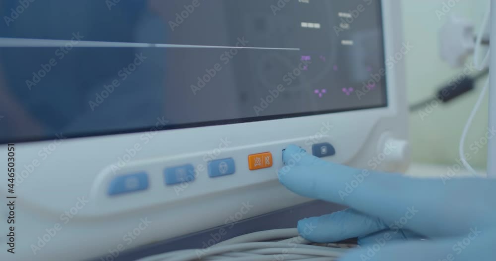Close-up buttons of the patient monitor. Medical hand in gloves is pushing a button. Close-up buttons of the patient monitor. Medical hand in gloves is pushing a button.