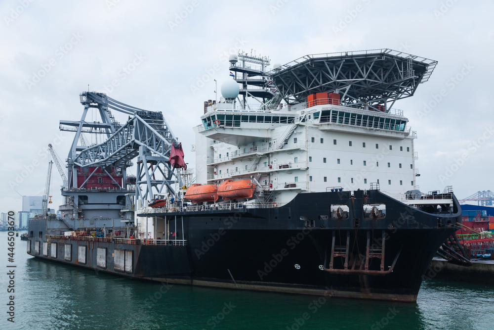 A large offshore vessel with a crane and a helipad is moored in the seaport of Rotterdam. A large offshore vessel with a crane and a helipad is moored in the seaport of Rotterdam.