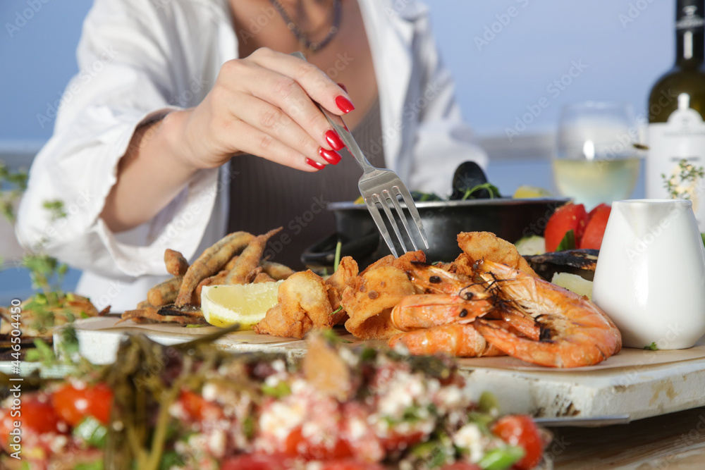 Young woman enjoying seafood platter during the sunset in the beach restaurant 