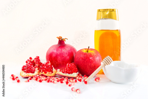Fototapeta Naklejka Na Ścianę i Meble -  Whole pomegranate, pomegranate seeds, red apple and honey, on white background. Jewish New Year symbols.