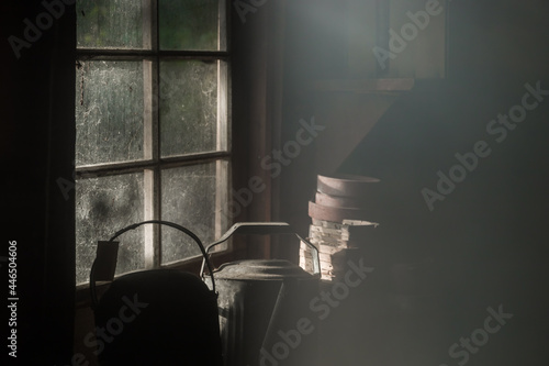 rays of the sun in the dirty window of an abandoned house. Inside view. Household items on the table. Cold tone