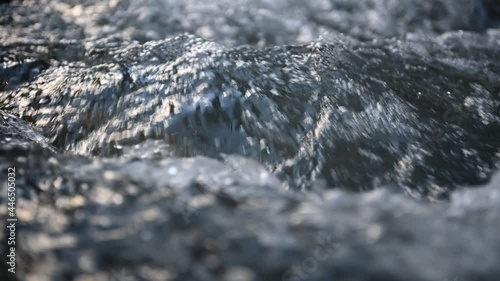 Slow motion of wild clear mountain river , stream flowing through rocks. Close up of river stones with flowing water, clean water flowing in a mountain river