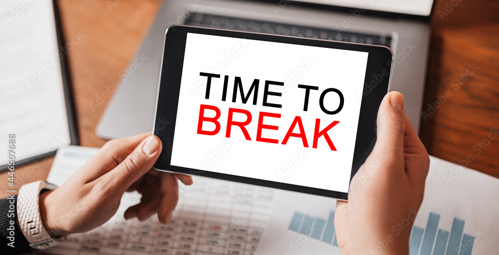 Man hands holding tablet with text TIME TO BREAK at workplace. Businessman working at desk with documents Man hands holding tablet with text TIME TO BREAK at workplace. Businessman working at desk with documents