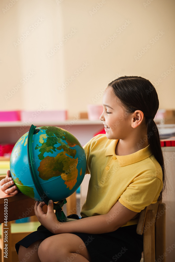 happy asian girl looking at globe in montessori school happy asian girl looking at globe in montessori school