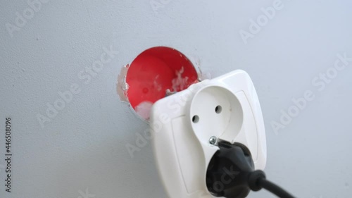 Incautious Careless Caucasian Male Tearing Out Household Loose Electric Outlet Socket From Wall Flush Mounted Electrical Junction Box by Pulling Power Cable Plug photo