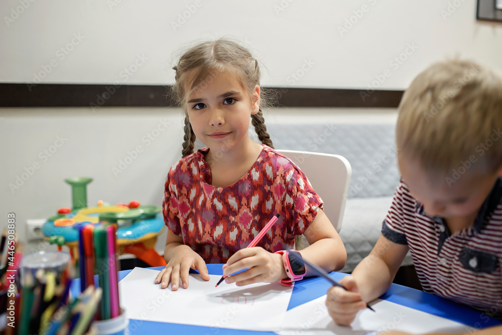A lefty girl and righty boy writing at the same desk and nudge each other with elbows, international left-hander day celebration, only lefties understand A lefty girl and righty boy writing at the same desk and nudge each other with elbows, international left-hander day celebration, only lefties understand