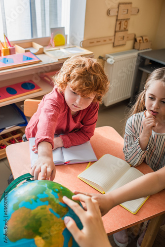 children looking at globe during lesson in montessori school