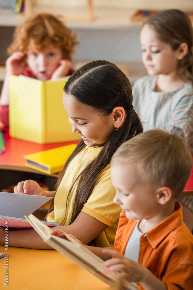 multiethnic kids reading books in classroom on blurred background multiethnic kids reading books in classroom on blurred background