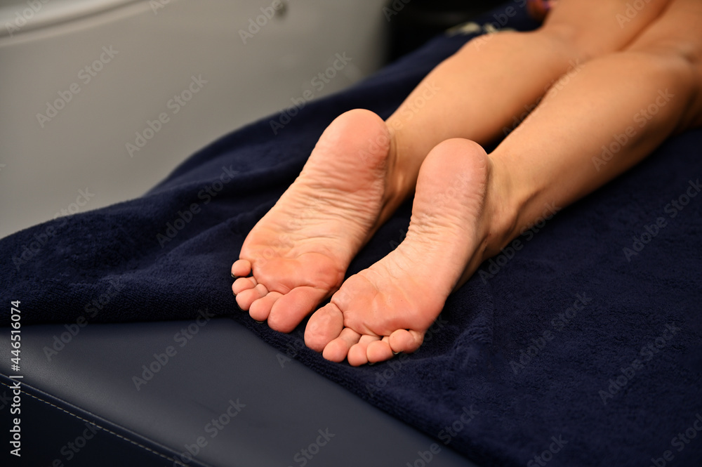 Woman's legs lying on a massage table in wellness spa resort - obrazy, fototapety, plakaty 