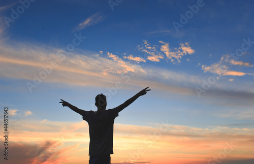 Silhouette of man with open arms and with sky after sunset in background. Concept of success, victory and gratitude.