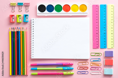 School stationery set on pink background top view. Colorful office supplies and blank paper notepad, Back to school concept.