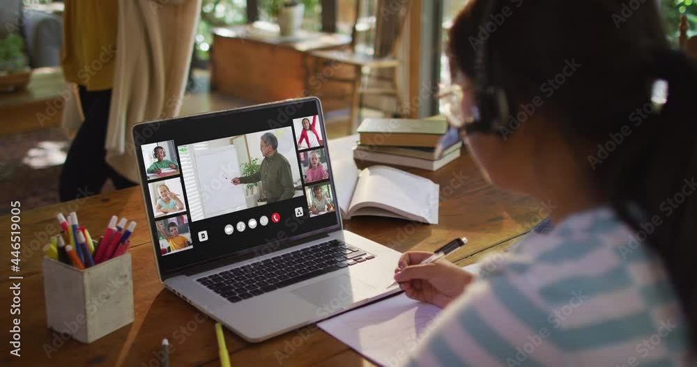 Schoolgirl using laptop for online lesson at home, with diverse teacher and class on screen