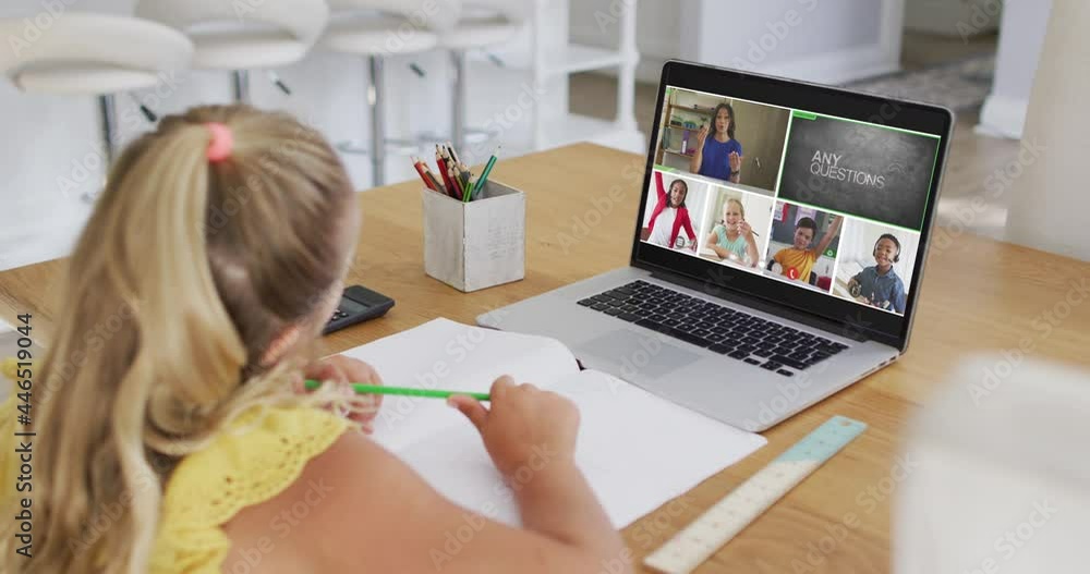 Schoolgirl using laptop for online lesson at home, with diverse teacher and class on screen
