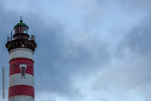 Red and white striped lighthouse on the background of a stormy sky. Free copy space for design or text