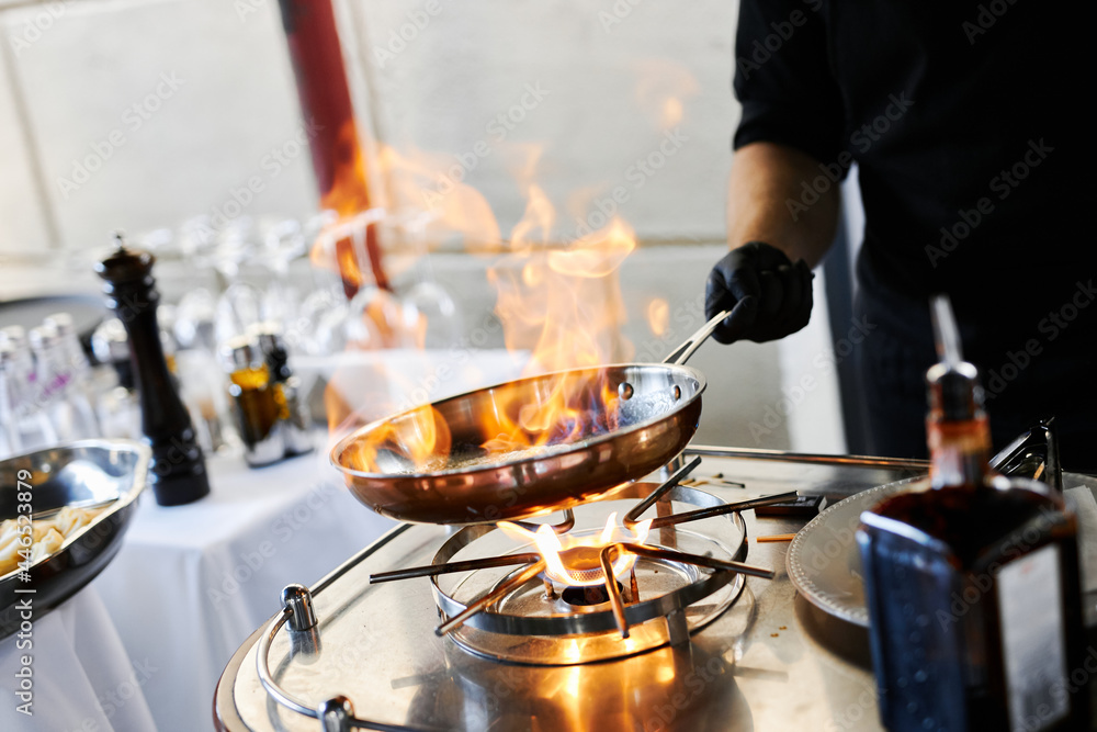 the chef prepares orange caramel on an open fire on the terrace of the restaurant the chef prepares orange caramel on an open fire on the terrace of the restaurant