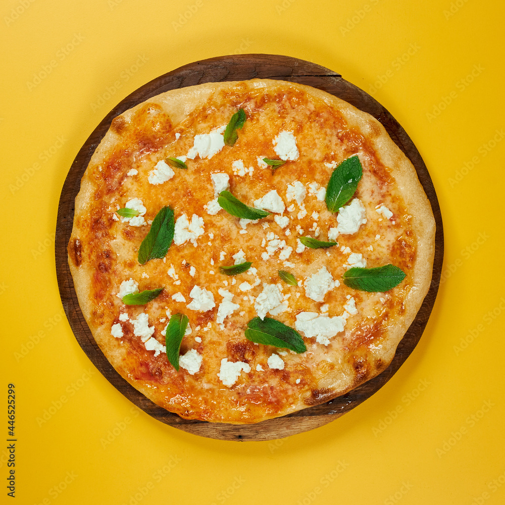 rustic pizza with feta cheese and herbs on wooden board and yellow background rustic pizza with feta cheese and herbs on wooden board and yellow background