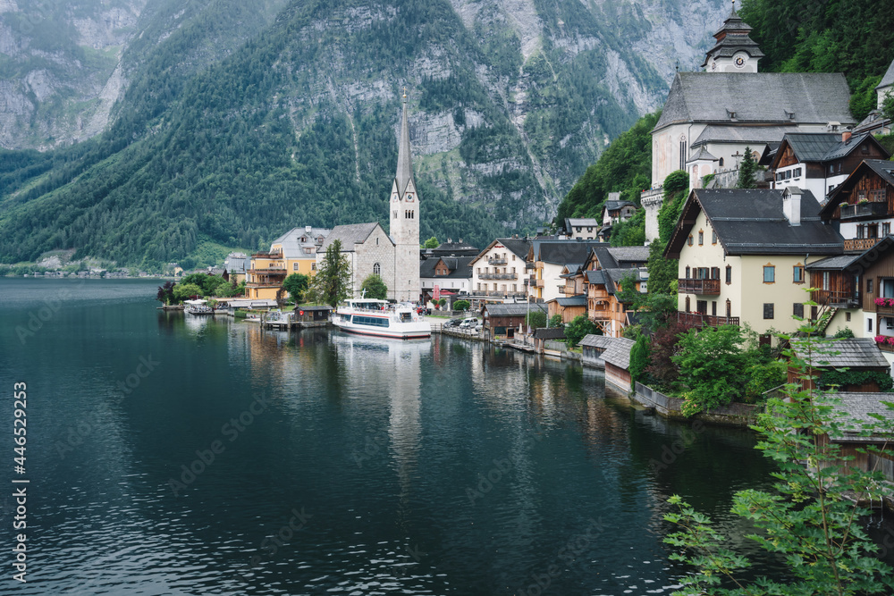Fototapeta premium Famous lake side view of Hallstatt village with Alps behind, Foliage leaves framed. Austria