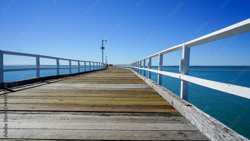 Perspective view along wooden pier toward the sea