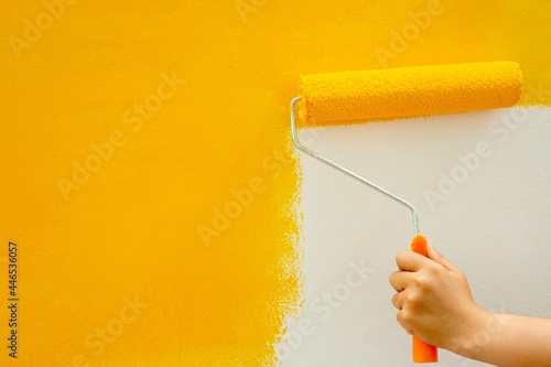 Use a roller to manually paint the yellow bedroom walls.