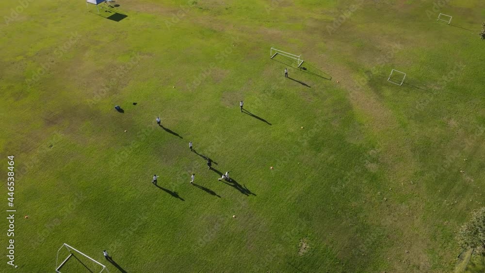Aerial drone shot showing team of children playing football soccer on green lawn during summer. Training in soccer club. Aerial drone shot showing team of children playing football soccer on green lawn during summer. Training in soccer club.