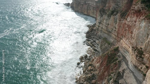 Aerial reveal of the beautiful old fortress Fort of São Miguel Arcanjo (St. Michael the Archangel) standing on a cliff surrounded by a wild sea photo