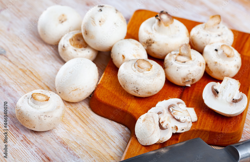 Fresh champignon mushrooms on a wooden cutting board. High quality photo