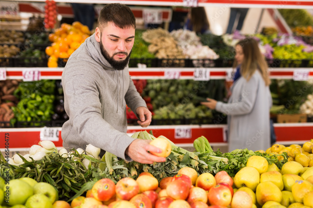 Male buyer is choosing apples in the grocery store. High quality photo