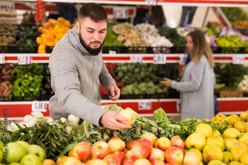 Male buyer is choosing apples in the grocery store. High quality photo
