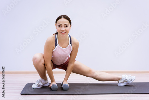 Happy caucasian woman in sportswear practices yoga at home against a wall background. The concept of a healthy lifestyle and inner spirit. Body concentration