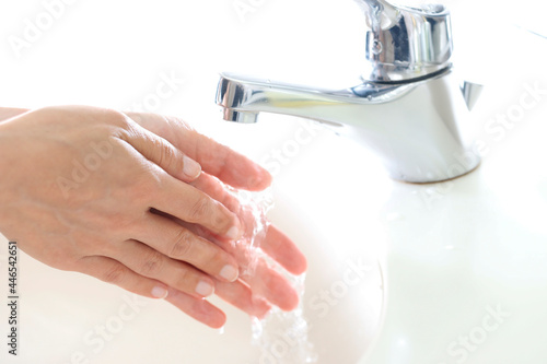 水道の蛇口と手を洗う人