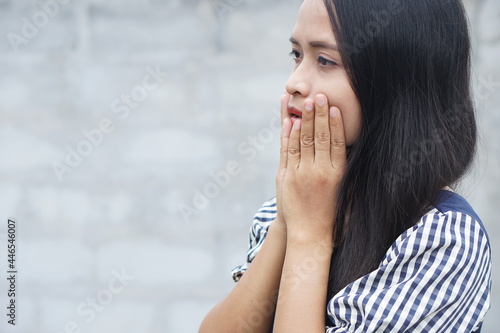 Young Asian woman got toothache on gray background