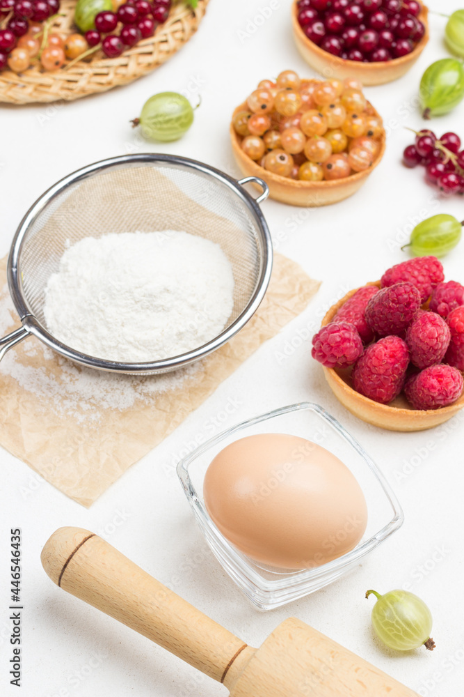 Flour in sieve, egg in small glass bowl. Tartlets with berries Flour in sieve, egg in small glass bowl. Tartlets with berries
