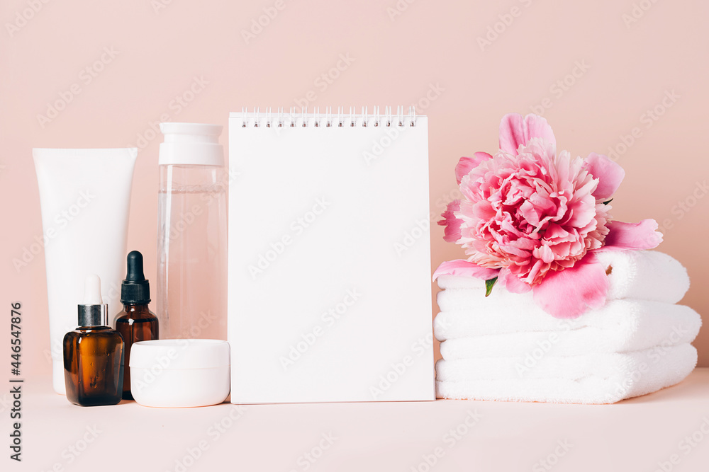 Womens accessories cream oil various cosmetics clean blank notebook on a table with flowers. Beauty concept Womens accessories cream oil various cosmetics clean blank notebook on a table with flowers. Beauty concept