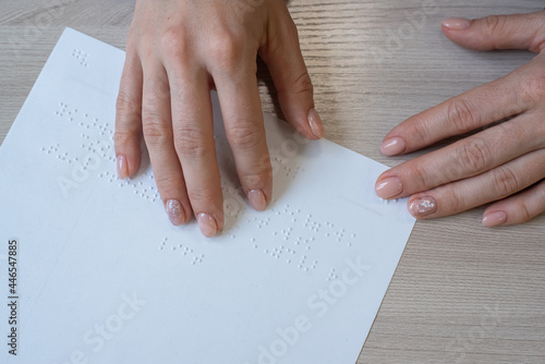 Close-up woman reads the text to the blind. Woman's hands on paper with braille code.