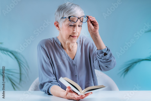 Senior Woman With Eyeglasses Having Problems with Book Reading. Indication for Cataract, Glaucoma, and Vision Loss in the Elderly.