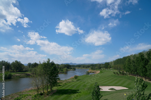 Riverside golf course under blue sky and white clouds